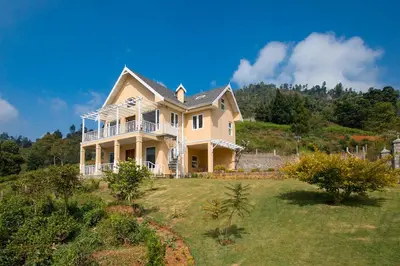 a large house on top of a hill at Yellow Tulip Hill Side Luxury Villa by LexStays in Coonoor
