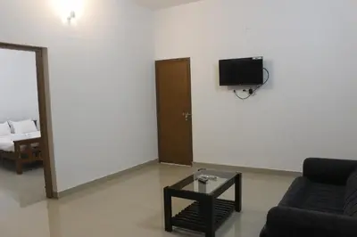 a living room with a couch and a tv on the wall at Zavon Holiday Home in Vythiri