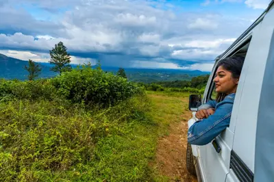 a woman looking out the window of a van at Zostel Plus Wayanad in Kalpetta