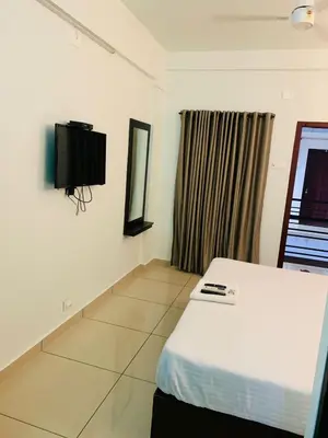 a bedroom with a bed and a tv on the wall at Apsara Residency in Perintalmanna