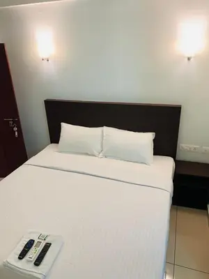 a bed with a remote control on top of it at Apsara Residency in Perintalmanna