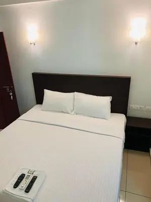 a bed with a remote control on top of it at Apsara Residency in Perintalmanna