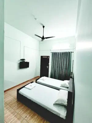 a bedroom with two beds and a ceiling fan at Apsara Residency in Perintalmanna