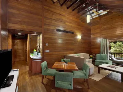 a living room with wooden walls and a table and chairs at The Tamara Coorg in Kakkabe