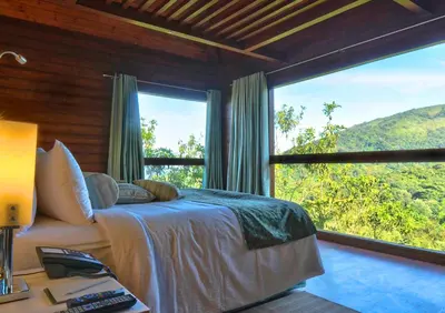 a bedroom with a bed and a large window at The Tamara Coorg in Kakkabe