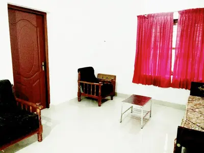 a living room with two chairs and a window at Nunu Homestay Guruvayoor in Guruvāyūr