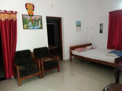 a small room with a bed and a chair at Nunu Homestay Guruvayoor in Guruvāyūr