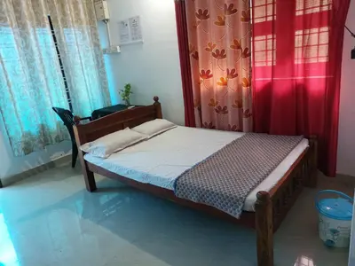 a small bed in a room with a red curtain at Nunu Homestay Guruvayoor in Guruvāyūr