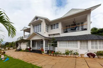a large white house with a courtyard at StayVista at Aashirwaad Villa in Coonoor