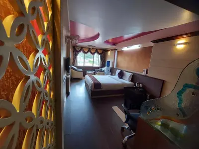 a bedroom with a bed and a room with a guitar at Astoria Residency in Ooty