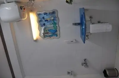 a white bathroom with a sink and a toilet at Astoria Residency in Ooty
