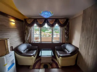 a living room with two leather chairs and a table at Astoria Residency in Ooty