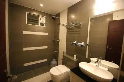 a bathroom with a white toilet and a sink at Hotel Le Sapphire in Sultan Bathery