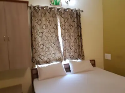 a bedroom with a bed with two pillows and a window at Comfort`s Pearl in Coimbatore