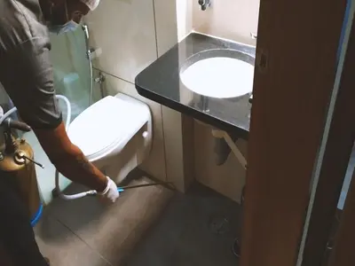 a man is washing a toilet in a bathroom at Heritage Inn in Mysore