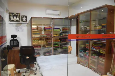 a glass room with a bed and a desk and a chair at Heritage Inn in Mysore