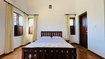 a bedroom with a bed in a room with windows at Pristine Hills in Meppādi