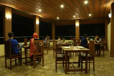 a group of people sitting at tables in a restaurant at Dakshin Ghats in Tariyod