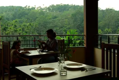 two women sitting at tables in a restaurant with a view at Dakshin Ghats in Tariyod