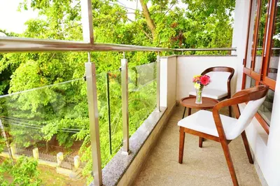 a balcony with a table and a chair and a window at UNNATHI SUITES in Mysore