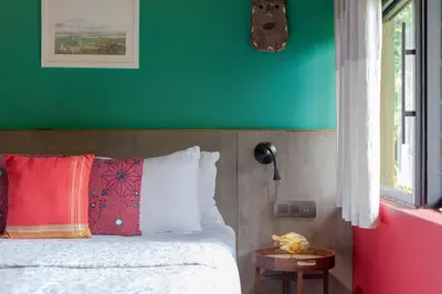 a bedroom with a green wall and a bed at StayVista at Toya Toya River View in Kozhikode