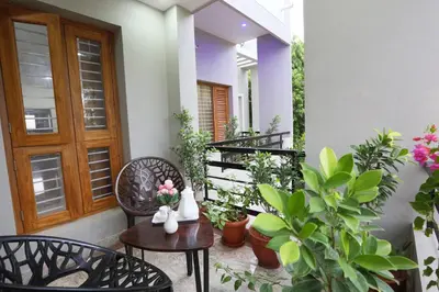 a porch with chairs and tables and potted plants at Like My Apartment in Mysore