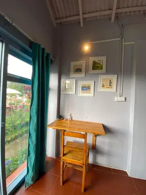 a wooden table in a room with a window at The Birdhouse Backpackers Hostel in Coonoor