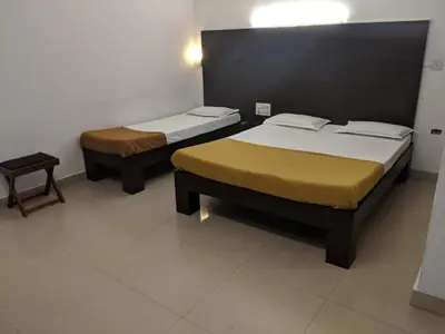 a room with two beds and a table and sidx sidx sidx at Aashraya in Mysore