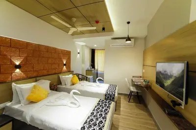 a hotel room with two beds and a flat screen tv at Bhavanam Regency Guruvayoor in Guruvāyūr