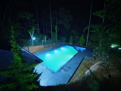 a swimming pool in a yard at night at Vintage Garden Resort in Sultan Bathery