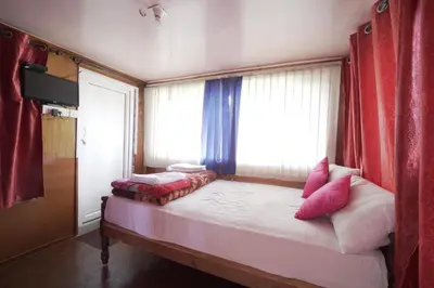 a bedroom with a bed with pink pillows and a window at Ganga's Sri Balaji Cottage in Ooty