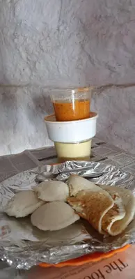 a plate of food with bread and a cup of sauce at Ganga's Sri Balaji Cottage in Ooty