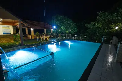 a swimming pool with blue water at night at Athirappilly Rainland Resort in Athirappilly