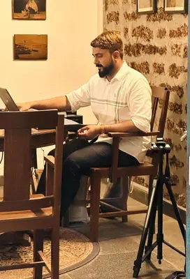a man sitting at a table with a laptop at Design Ashram in Kozhikode