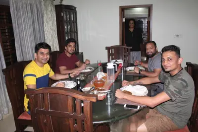 a group of men sitting around a table at Whistling Woods Farm Stay in Kushālnagar