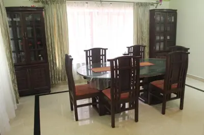 a dining room with a table and chairs and a window at Whistling Woods Farm Stay in Kushālnagar