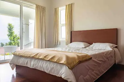 a bedroom with a large bed with a large window at StayVista at The Lilly Ooty with Breakfast in Ooty