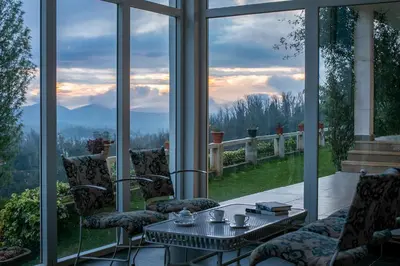 a screened in porch with a table and chairs at StayVista at The Lilly Ooty with Breakfast in Ooty
