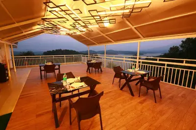 a restaurant with tables and chairs on a balcony at Bonita Banasura in Vythiri