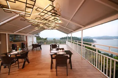 a restaurant with tables and chairs on a balcony at Bonita Banasura in Vythiri