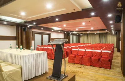 a conference room with red chairs and a podium in it at KPM TRIPENTA HOTEL in Kozhikode