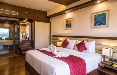 a bedroom with a large bed with white sheets at KPM TRIPENTA HOTEL in Kozhikode