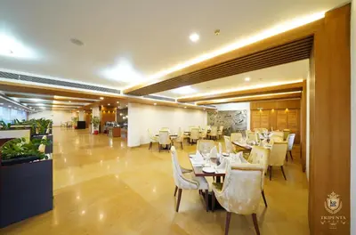 a restaurant with tables and chairs in a room at KPM TRIPENTA HOTEL in Kozhikode