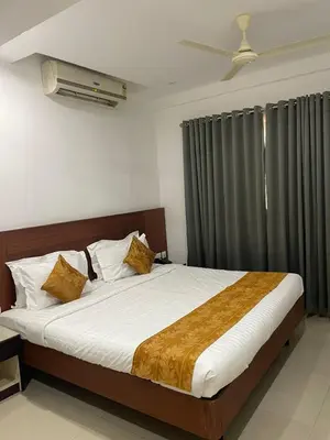 a bedroom with a bed with white sheets and a window at Kallada Sangeetha Hotels in Trichūr