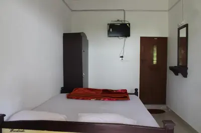 a bedroom with a bed with a red blanket on it at Woodside Homestay Wayanad in Batheri