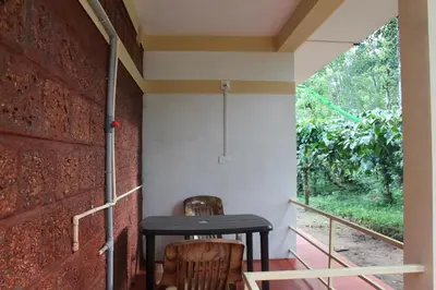 two chairs and a table on a porch with a window at Woodside Homestay Wayanad in Batheri