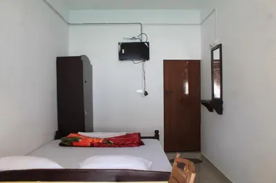 a small bedroom with a bed and a tv at Woodside Homestay Wayanad in Batheri
