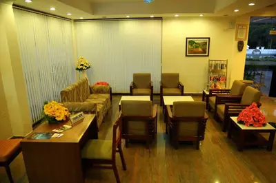 a waiting room with couches and a table and chairs at Kallada hotels in Trichūr