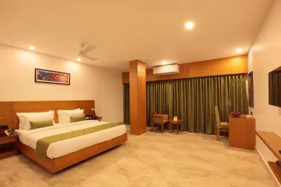 a hotel room with a bed and a table and chairs at Hotel Park Residency Thrissur in Trichūr
