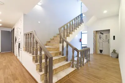 a staircase in a home with white walls and wood floors at Super Townhouse Srm Kuppakonam Pudur in Coimbatore
